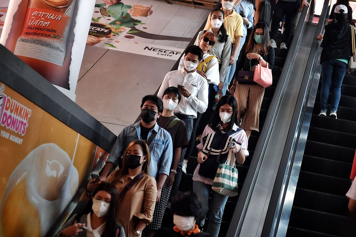 This photo taken on 18 February 2020 shows people wearing protective facemasks, amid concerns of the COVID-19 coronavirus outbreak, as they ride on an escalator during the morning commute in Bangkok. Photo: AFP