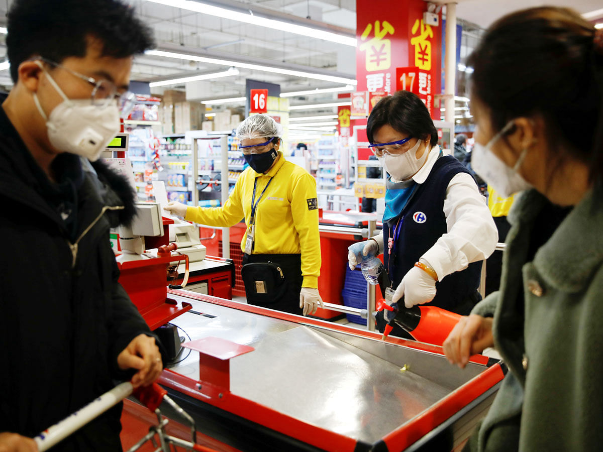 A staff member wearing a face mask sanitizes a cashier counter at a supermarket, as the country is hit by an outbreak of the new coronavirus, in Beijing, China on 19 February. Photo: Reuters