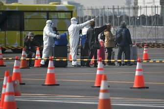 Workers in protective suits direct passengers with their luggages from the Diamond Princess cruise ship, in quarantine due to fears of new COVID-19 coronavirus, at Daikoku pier cruise terminal in Yokohama on 20 February 2020. Japan hit back at criticism over `chaotic` quarantine measures on the coronavirus-riddled Diamond Princess cruise ship, as fears of contagion mount with more passengers dispersing into the wider world. Photo: AFP