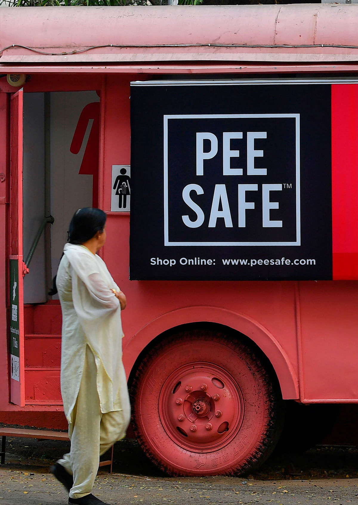 This photo taken on 9 February 2020 shows a woman walking past a mobile toilet on a bus at a public park in Pune. Launched in 2016 by entrepreneurs Ulka Sadalkar and Rajeev Kher, the `Ti Toilet` project -- `ti` means `her` in the local Marathi language -- has 11 mobile washrooms, which are on average used by more 200 women daily. Photo: AFP