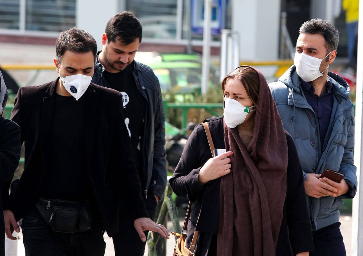 Iranians, some wearing protective masks, wait to cross a street in the capital Tehran on 22 February, 2020. Photo: AFP