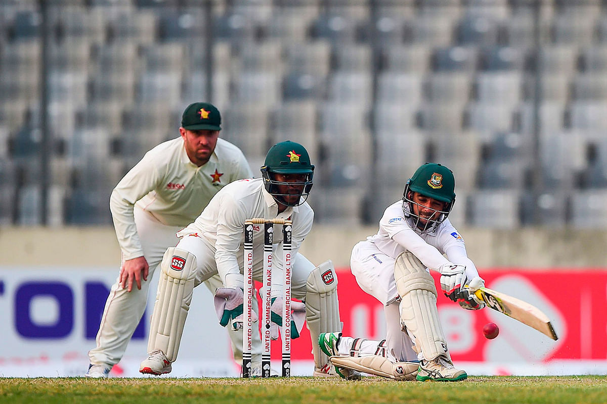 Bangladesh`s captain Mominul Haque (R) plays a shot as Zimbabwe`s Regis Chakabva (C) and Brendan Taylor (L) look on during the second day of a Test cricket match between Bangladesh and Zimbabwe at the Sher-e-Bangla National Cricket Stadium in Dhaka on 23 February, 2020. Photo: AFP
