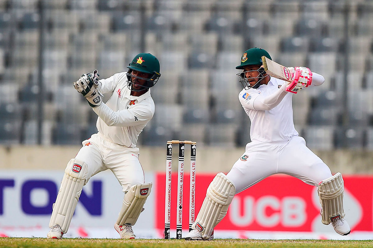 Bangladesh`s Mushfiqur Rahim (R) plays a shot as Zimbabwe`s Regis Chakabva (L) looks on during the second day of a Test cricket match between Bangladesh and Zimbabwe at the Sher-e-Bangla National Cricket Stadium in Dhaka on 23 February, 2020. Photo: AFP