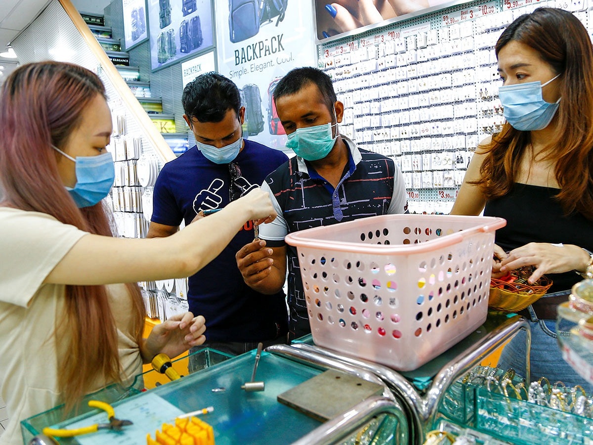 Migrant workers from Bangladesh have their watches fixed at a shop in Singapore on 23 February 2020. Photo: Reuters