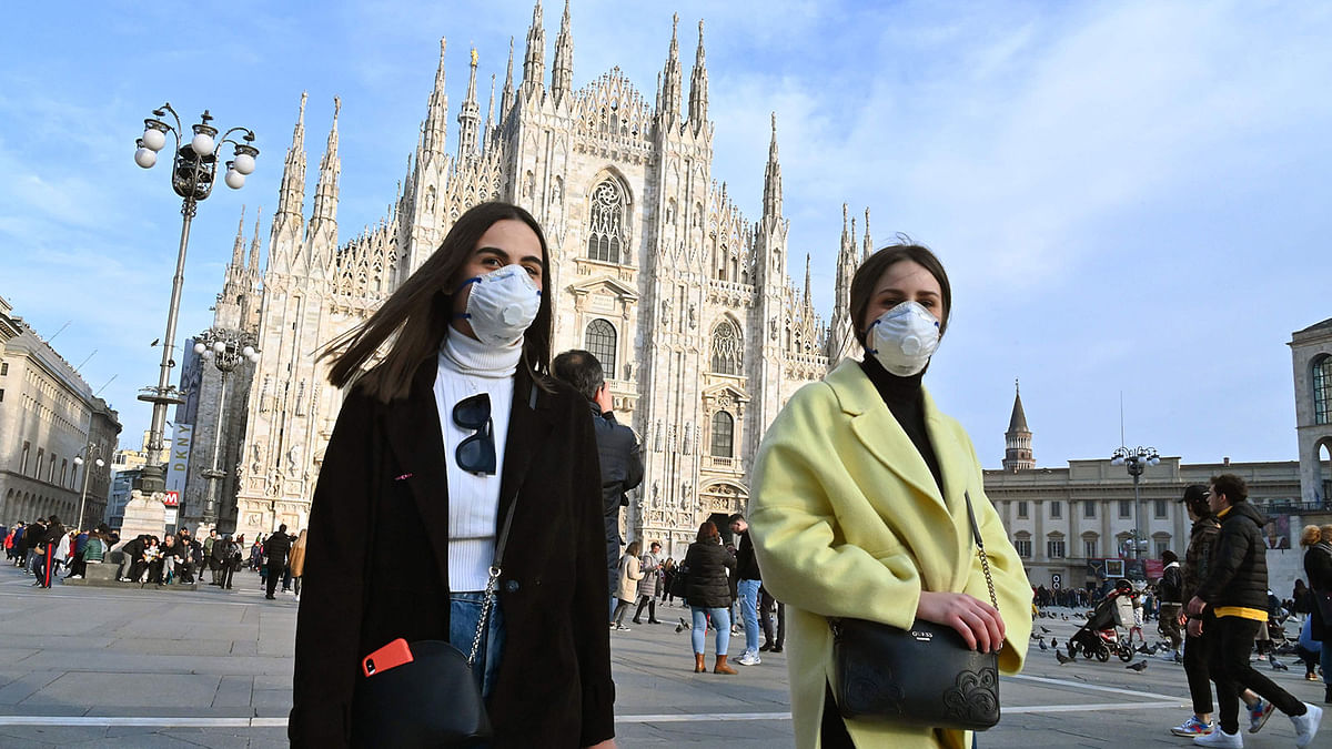 Women wearing a respiratory mask walk across Piazza del Duomo in central Milan on 23 February 2020. Tens of thousands of Italians prepared for a weeks-long quarantine in the country’s north on 23 February as nerves began to fray among the locals faced with new lockdown measures. Photo: AFP