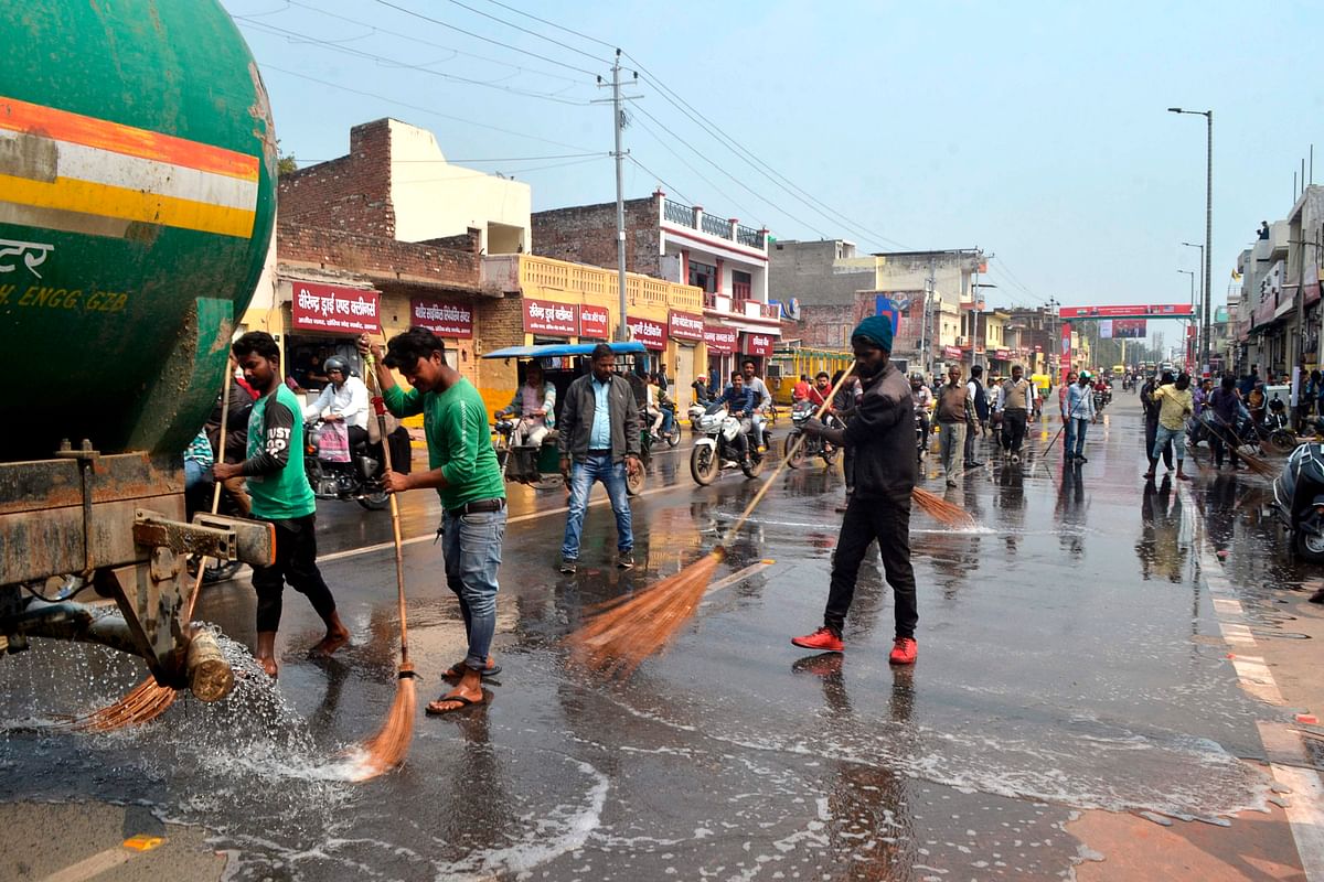 Workers wash a road with water near Kheria Airport in Agra on 23 february, ahead of US president Donald Trump first official visit to India. Photo: AFP