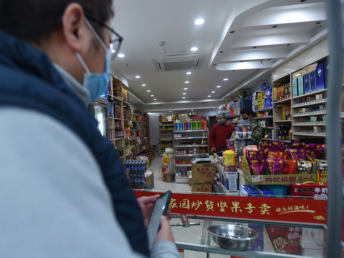 A customer wearing a face mask buys goods at a shop in Wuhan, the epicentre of the novel coronavirus outbreak, Hubei province, China on 23 February 2020. Photo: Reuters