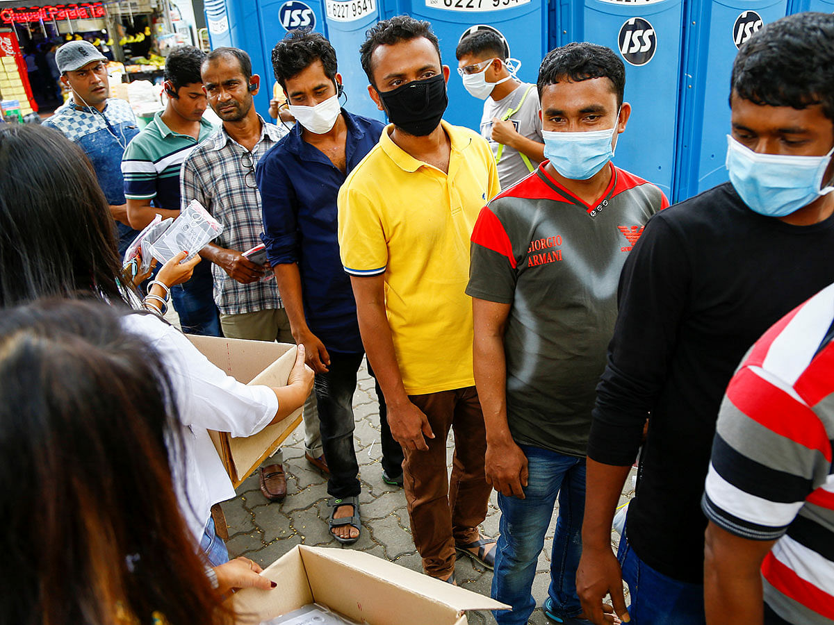 Migrant workers, mostly from Bangladesh, queue to collect free masks and get their temperatures taken in Singapore on 23 February 2020. Photo: Reuters