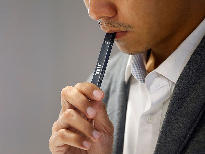 A shopkeeper demonstrates smoking a Juul brand vaping pen to customers at a Juul shop in Jakarta. Photo: Reuters