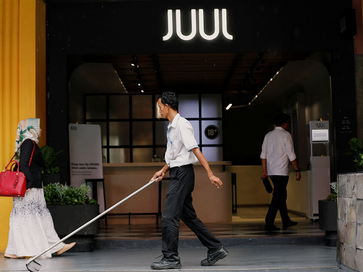 A worker sweeps as people walk pass the Juul shop at a shopping mall in Jakarta. Photo: Reuters