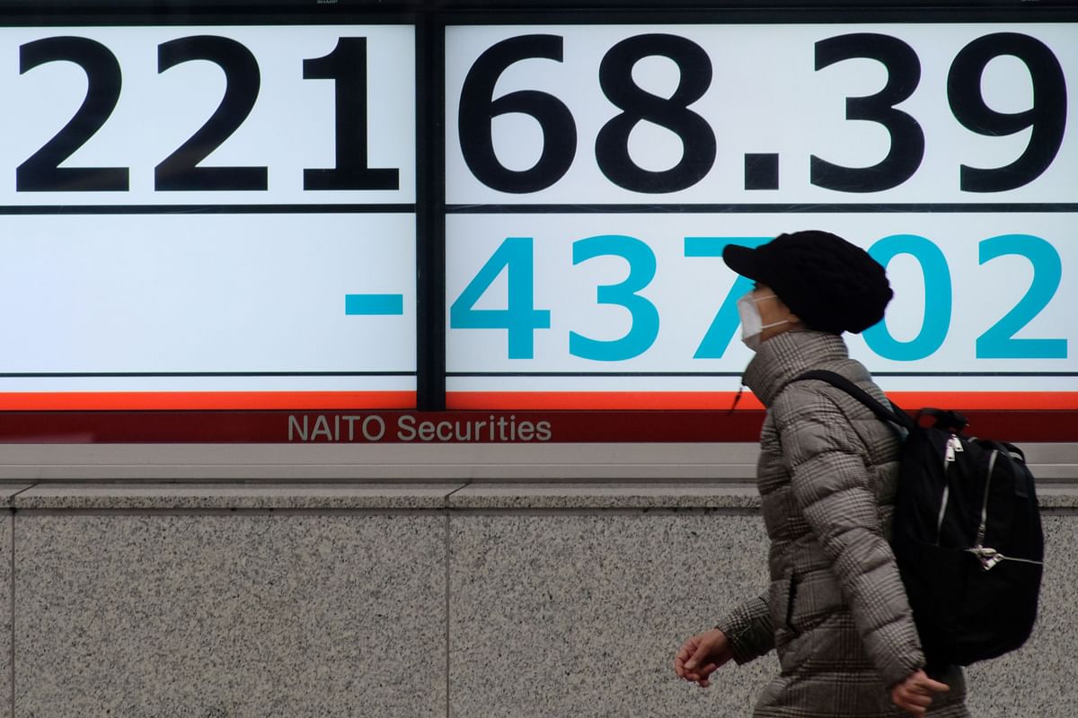 A pedestrian walks past an electronic quotation board displaying share prices of the Nikkei 225 Index in Tokyo on 26 February 2020. Photo: AFP