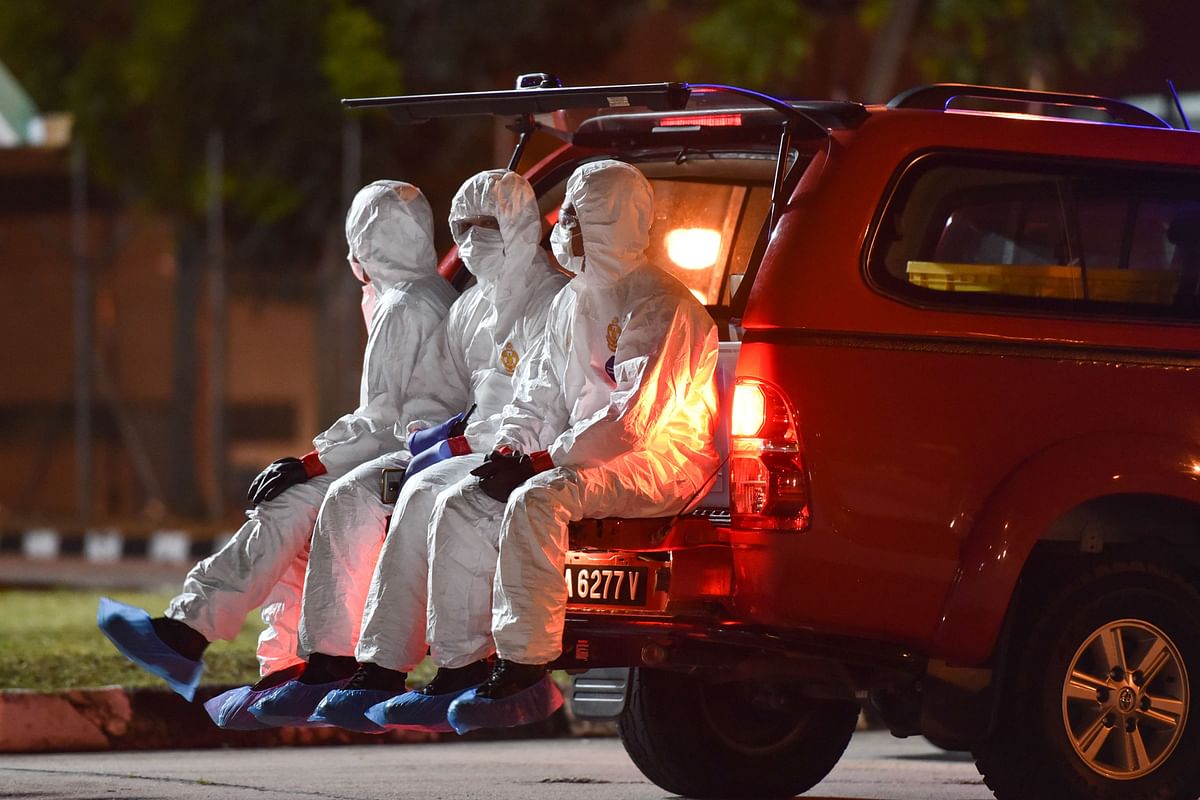This handout photo from Malaysia`s health ministry taken and released on 26 February 2020 shows health workers wearing protective suits riding in the back of a vehicle as the second batch of Malaysian nationals, evacuated from the Chinese city of Wuhan, the epicentre of the COVID-19 novel coronavirus outbreak, arrive at Kuala Lumpur International Airport in Sepang. Photo: AFP