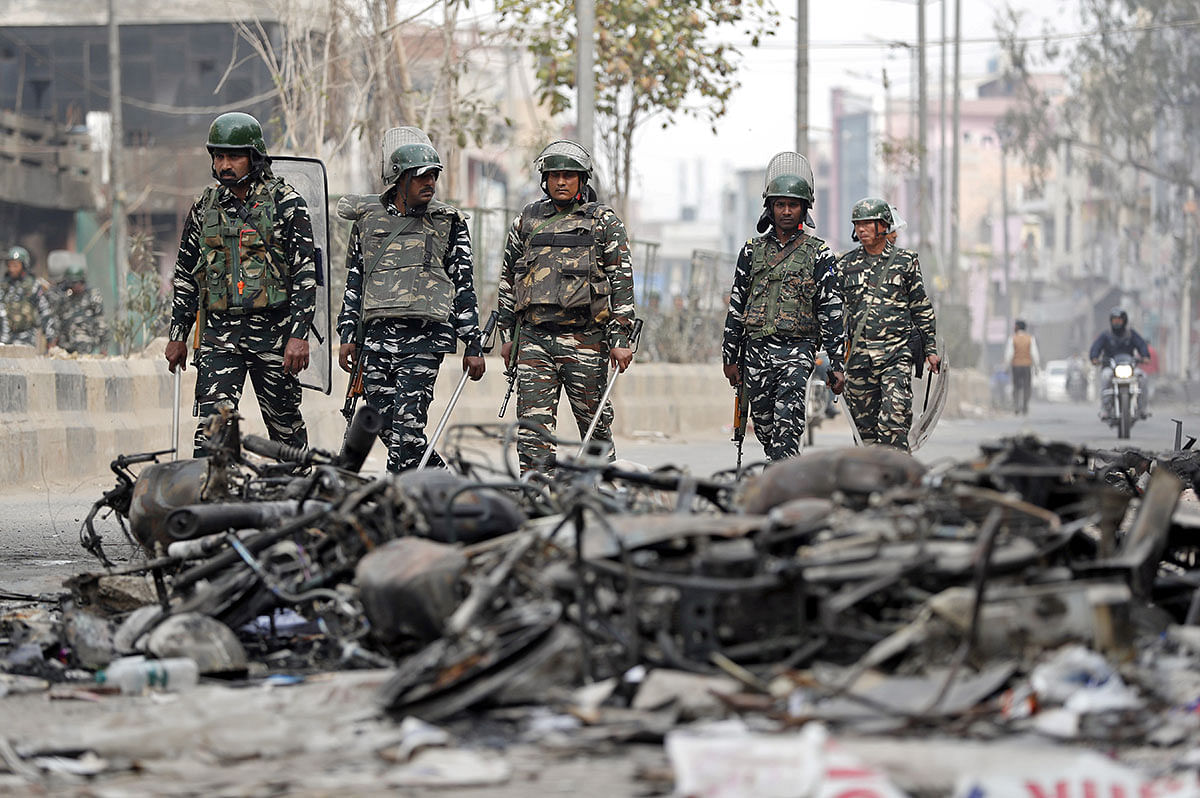 Security forces patrol past charred vehicles in a riot affected area following clashes between people demonstrating for and against a new citizenship law in New Delhi. Photo: Reuters